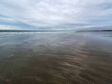 Kuzey Denizi kıyısında Hoek van Holland 'da bulutlu gökyüzü ve Hollanda kıyılarında alçak gelgitle