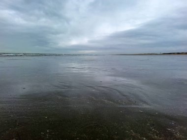 Kuzey Denizi kıyısında Hoek van Holland 'da bulutlu gökyüzü ve Hollanda kıyılarında alçak gelgitle