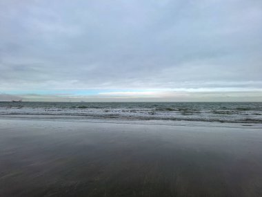 Kuzey Denizi kıyısında Hoek van Holland 'da bulutlu gökyüzü ve Hollanda kıyılarında alçak gelgitle