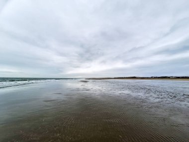 Kuzey Denizi kıyısında Hoek van Holland 'da bulutlu gökyüzü ve Hollanda kıyılarında alçak gelgitle