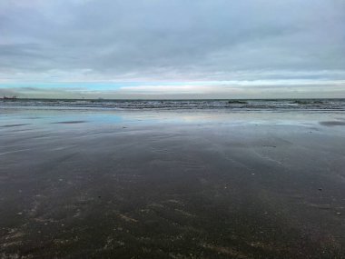 Kuzey Denizi kıyısında Hoek van Holland 'da bulutlu gökyüzü ve Hollanda kıyılarında alçak gelgitle