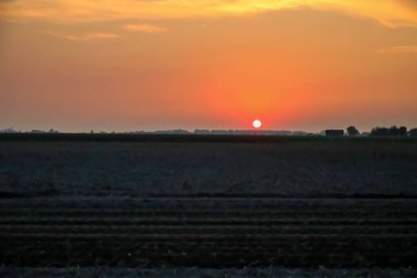 Hollanda 'da sıcak bir günün ardından Hazerwoude Köyü' nün üzerinde gün batımı