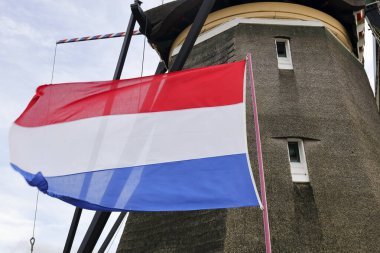 Hollanda 'da Zevenhuizen' de geleneksel bir yel değirmeni önünde Hollanda bayrağı