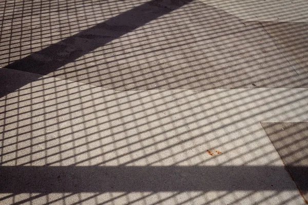 セメントフロア上の金属フェンスのネット形状の影 コンクリート上の手すりの鋼線を通してこぼれた光 — ストック写真