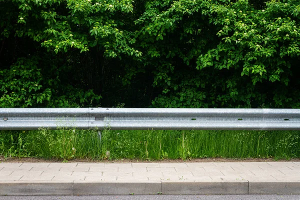 stock image Sidewalk, highway guard rail, green grass and bushes. Background for copy space.