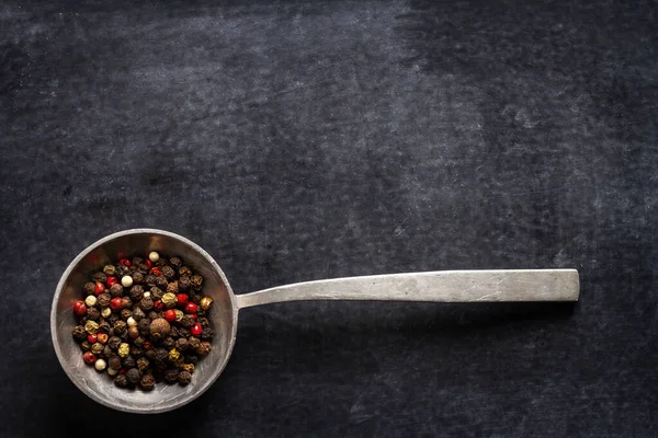 stock image Big old spoon with peppercorn on black background. Flat lay. Top view. Food concept. Dark mood food photography.