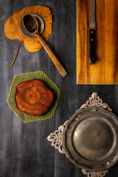 stock image Old cutting board with linen napkin and spoon on black wooden background. Flat lay. Top view. Copy space.