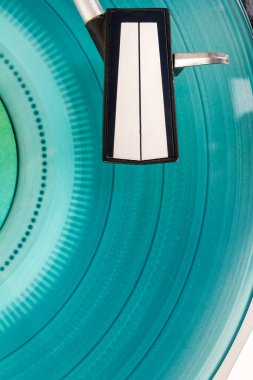 Close up of turntable needle on a vinyl record. Turntable playing vinyl. Needle on rotating cyan vinyl. clipart