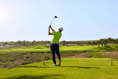 Golf sahasında golf oynamaya hazır bir golfçü. Golf sopalı bir golfçü mükemmel atış için topa vuruyor..
