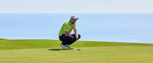 彼の手にパターで緑の上にゴルファー 緑のプレーヤーは フラグに向かってボールを目指す前に 穴からの斜面や距離を評価します — ストック写真