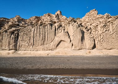 Santorini adasının güney ucundaki Vlychada sahilinde rüzgar ve deniz tarafından şekillendirilmiş yüksek beyaz uçurumlar, çakıl taşlarıyla karıştırılmış gri kum.
