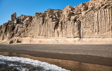 Santorini adasının güney ucundaki Vlychada sahilinde rüzgar ve deniz tarafından şekillendirilmiş yüksek beyaz uçurumlar, çakıl taşlarıyla karıştırılmış gri kum.
