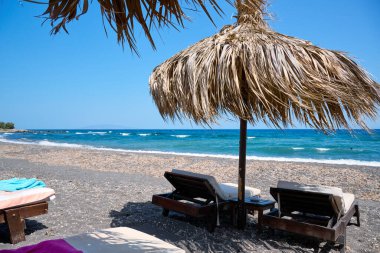 Paralia Karterados, sazdan şemsiyeli vahşi volkanik kum plajı. Yunan adaları, Santorini, Avrupa tatilleri.