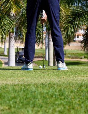 Golf sahasında golf oynamaya hazır bir golfçü. Golf sopalı bir golfçü mükemmel atış için topa vuruyor..