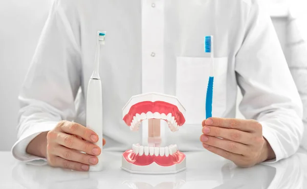 Οδοντίατρος Κρατώντας Δύο Οδοντόβουρτσες Ένα Εγχειρίδιο Και Ένα Ηλεκτρικό — Φωτογραφία Αρχείου