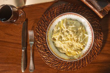 Beyaz peynir soslu nefis bir makarna. Arka planda eski kitaplar