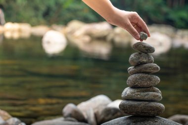 Woman's hand balancing stones in waterfall. Zen  balance and meditation clipart