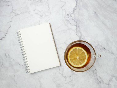 Lemon tea and book on marble texture background.