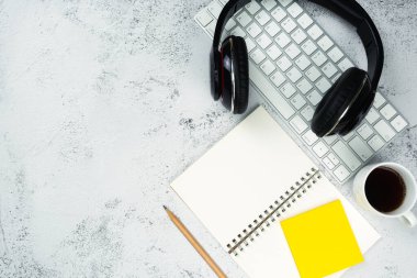 Ofis masasının üstünde klavye bilgisayarı, kitap ve kulaklıkla en üst görüntü. İş ve finans kavramı. İş yeri. Boş fotokopi alanı olan düz bir yer. Taş dokusu.
