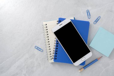 Boş maket ekranlı cep telefonu ve taş desenli arkaplan üzerine kitap. Üst görünüm. düz yat.