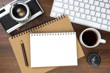 Ofis masasının üstünde klavye bilgisayarı, kitap ve eski kamerayla üst görüntü. İş ve finans kavramı. İş yeri. Boş fotokopi alanı olan düz bir yer. Ahşap doku.