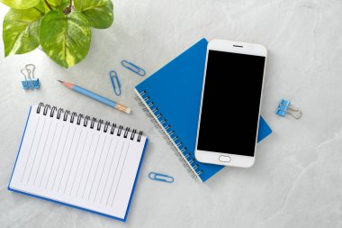 Cep telefonu, boş bir ekran ve taş dokusu üzerine bir kitap. Çalışma masası. Üst Manzara. Düz yatıyordu.