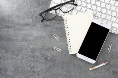 Cep telefonu, boş bir ekran ve taş dokusu üzerine bir kitap. Çalışma masası. Üst Manzara. Düz yatıyordu.