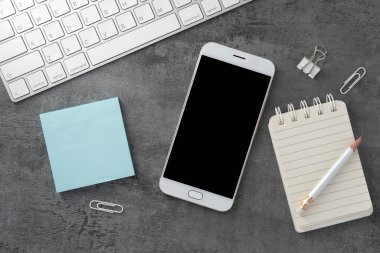 Cep telefonu, boş bir ekran ve taş dokusu üzerine bir kitap. Çalışma masası. Üst Manzara. Düz yatıyordu.
