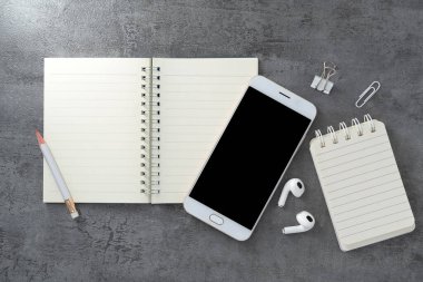 Cep telefonu, boş bir ekran ve taş dokusu üzerine bir kitap. Çalışma masası. Üst Manzara. Düz yatıyordu.