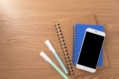 Boş model ekranlı cep telefonu ve ahşap dokular üzerine kitap. Çalışma masası. Üst Manzara. düz yat.