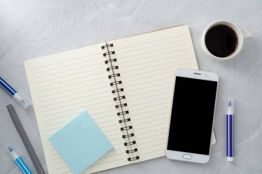 Cep telefonunun arka planında boş bir ekran, kitap ve kahve var. Çalışma masası. Üst Manzara. Düz yatıyordu.