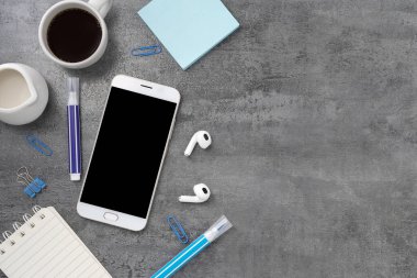 Cep telefonunun arka planında boş bir ekran, kitap ve kahve var. Çalışma masası. Üst Manzara. Düz yatıyordu.