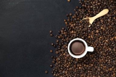 Kahve çekirdekleri ve fincanlar siyah arka planda. Metnin için kopyalama alanı