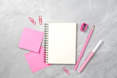 Not defteri, pembe yapışkan not ve taş dokusu arka planında kırtasiye malzemesi. Çalışma masası alanı