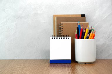 Defter, kalem bardağı ve takvim masanın üstünde. Çalışma masası alanı