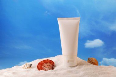 Krema tüpü ve kabuklar kumun üzerinde. Model için kozmetik ürün