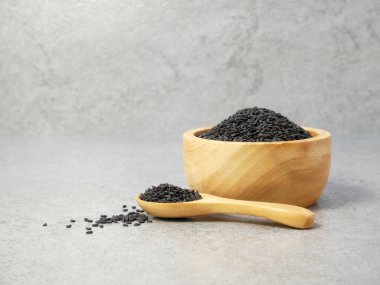 Tahta kaşıkta siyah susam tohumları ve taş desenli arka planda kâse