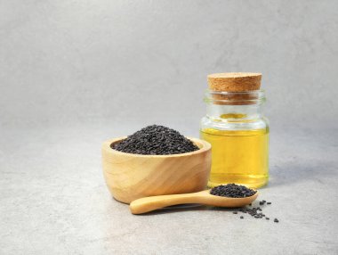 Siyah susam tohumları ve taş dokusunda yağ şişesi.
