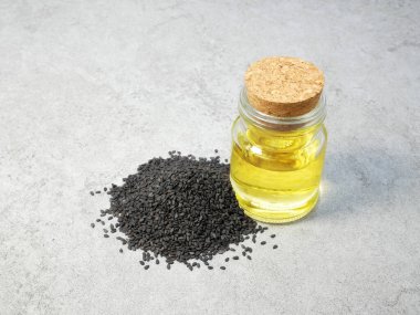 Siyah susam tohumları ve taş dokusunda yağ şişesi.