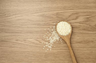 Tahta bir arka planda kaşıkta beyaz susam.