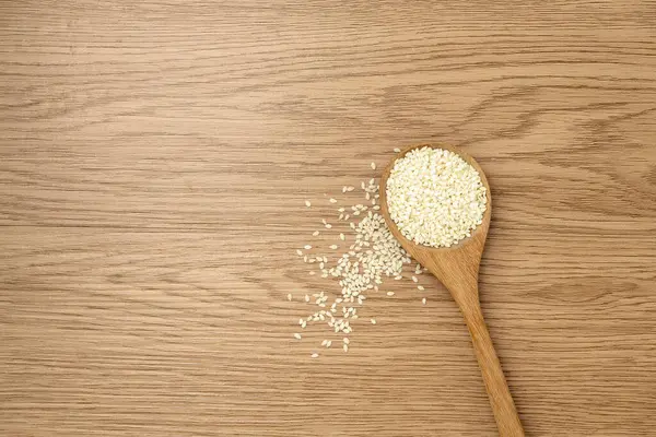Tahta bir arka planda kaşıkta beyaz susam.