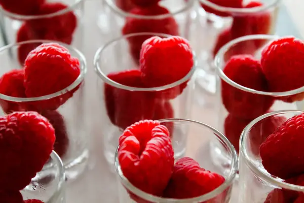 stock image Close-up of fresh raspberries placed in small glass cups, showcasing their vibrant red color and texture. Ideal for food photography or culinary presentations.