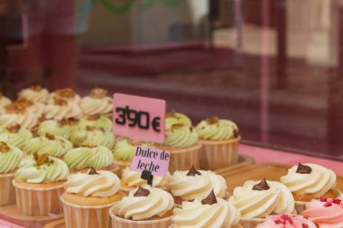 Fırın vitrininde renkli keklerin sergilenmesi. Kekler kremayla kaplı. Dulce de leche ve şam fıstığı aromalı..