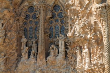 Tarihi bir binanın ön cephesindeki karmaşık heykellerin ve boyalı camların yakın görüntüsü, ayrıntılı dini figürler ve dekoratif tasarımlar sergileniyor..