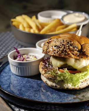 Bir gurme hamburgerin tadını çıkarın, patates kızartması ve sosla. Yerel bir lokantanın havasını ve tadını vurgulayın..