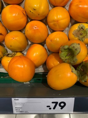 Orange fruit persimmon, sharon, kaki in a German store on the counter with a price tag of 0.79 euros.