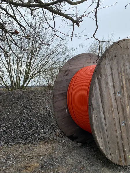 A wooden reels with ann orange cable on a construction site. Side view.