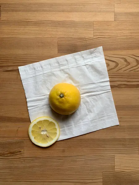 Yarım limon ve bir dilim limon beyaz bir peçetenin üzerinde ortadaki ahşap bir masanın arka planında yan yana uzanıyorlar. Yukarıdan bak. Metin için yer