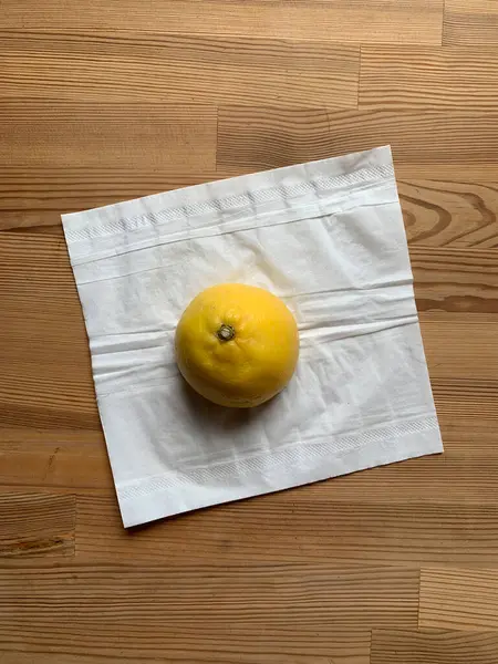 Yarım limon beyaz bir kağıt peçetenin üzerinde ortadaki ahşap bir masanın arka planında yatıyor. Yukarıdan bak. Metin için yer