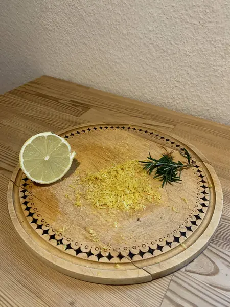 Yarım limon ve taze rendelenmiş limon lezzeti ve ahşap bir masanın üzerinde yuvarlak ahşap otantik bir tahta üzerinde bir çift taze biberiye. Beyaz duvar, metin için boşluk